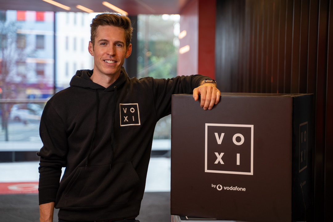 Scott Currie, Head of VOXI Mobile, posing by VOXI sign.